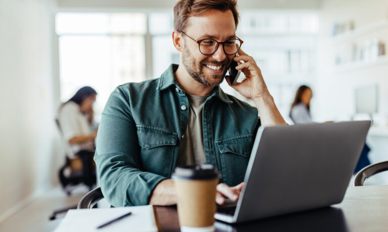 Male software designer speaking to a client on the phone in an office